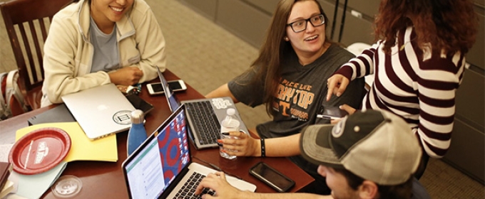 photo of four people at a table, with laptop