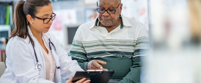 photo of doctor with patient, both looking at clipboard