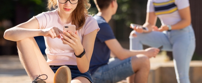 young people outside on their phones