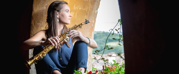 photo of woman sitting in arch opening with musical instrument