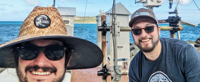 photo of two men, with instruments and sea in background