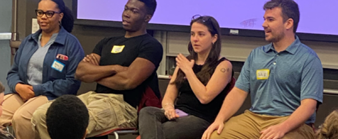 photo of four people seated with name tags, audience