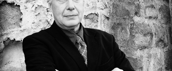 black and white photo of man, with stone wall