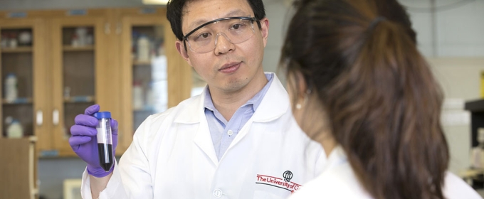 photo of two people in lab coats, foreground figure with back turned to camera