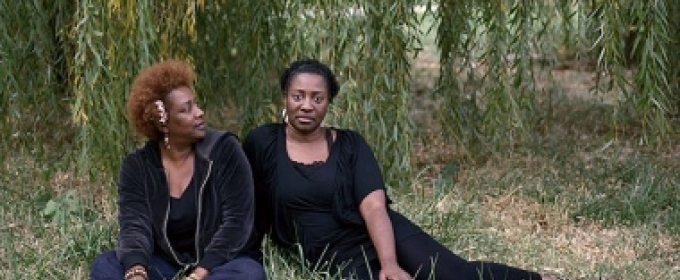 two women sitting beneath a tree