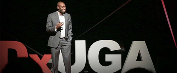 photo of man on stage talking to an audience in foreground