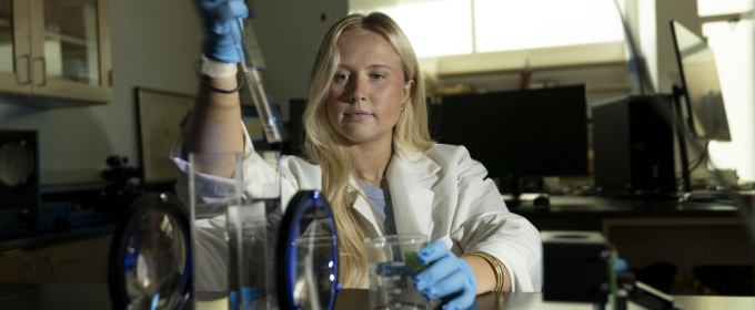 photo of woman in lab with instruments, white coat, pipette