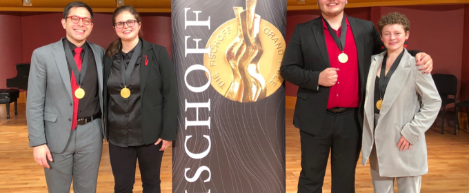 photo of four people with medals and banner in performance hall