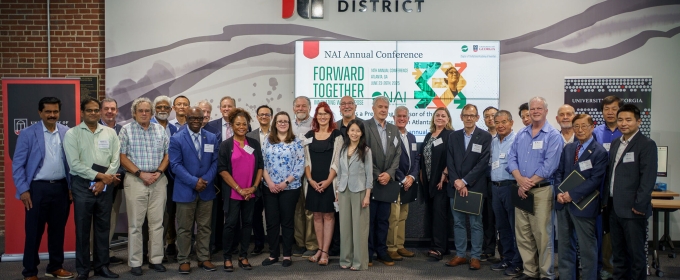 group photo of 31 people, indoors, sign in background