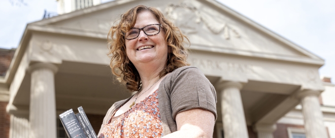 photo of woman holding books, with building, day