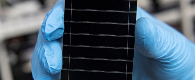 photo of tiny solar cell, held by blue-gloved hand