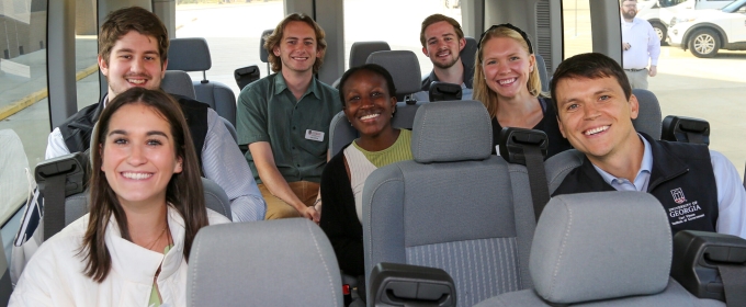 photo off seven smiling students inside a van