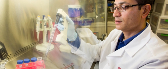 photo of man in lab coat with tubes in isolation chamber