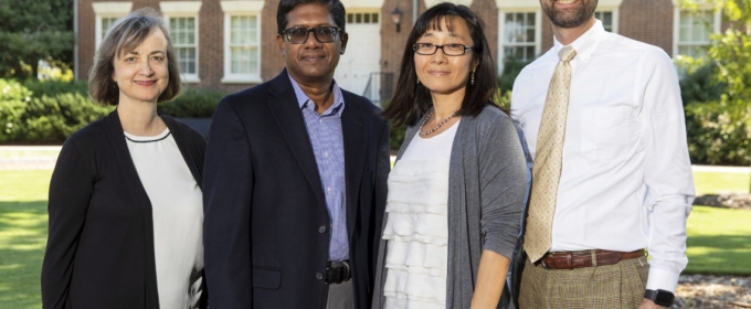 photo of four people, with Old College in background