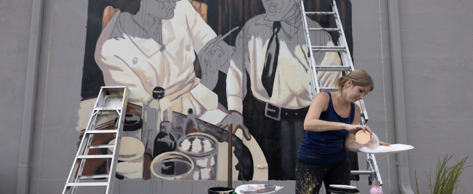 photo of woman mixing paint with mural, ladders, and paint cans