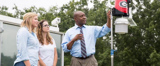 photo of man and two women with weather station