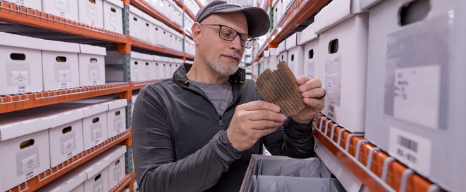 photo of man in aisle of shelves with boxes