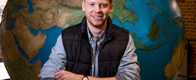 photo of man in front of globe