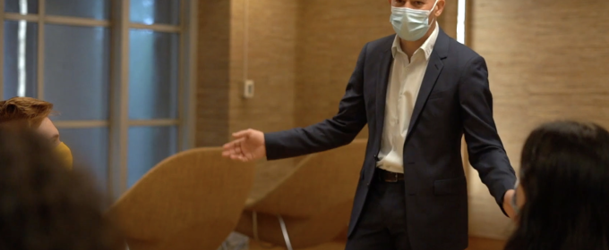 photo of man with mask standing at table, arms spread