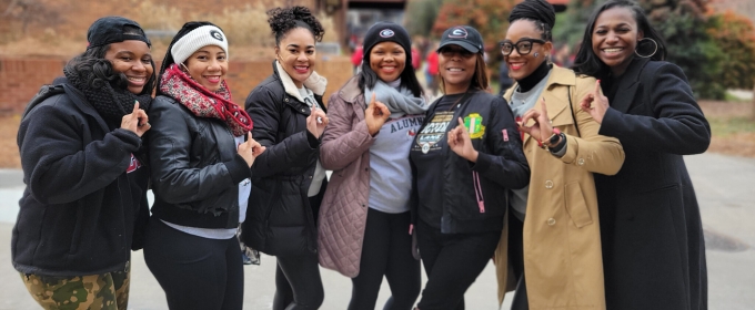 photo of seven women outdoors, with stadium in background