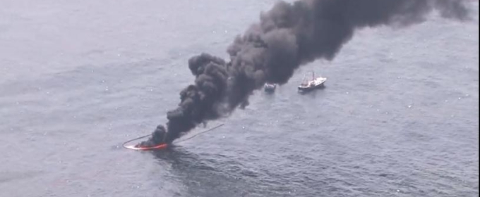 aerial photo of black smoke rising from the ocean water