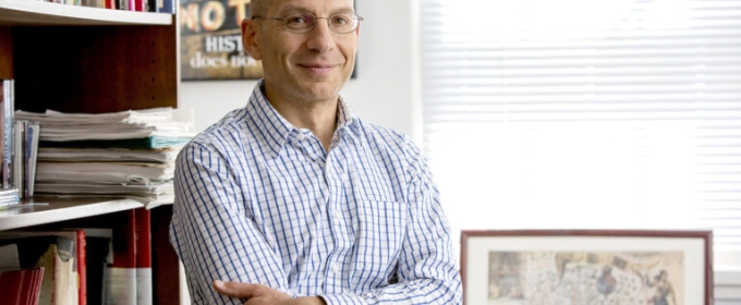 photo of man in office with framed map, books