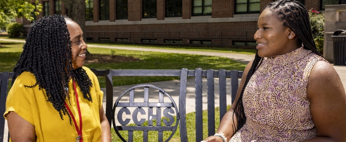 photo of two women sitting on bench outdoors, day