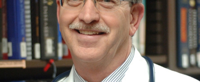 headshot of man, with books in background