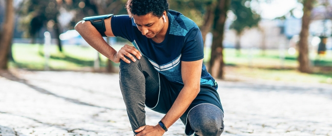 photo of runner kneeling to touch ankle