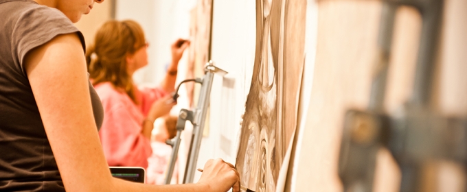 photo of people drawing on paper attached to a wall