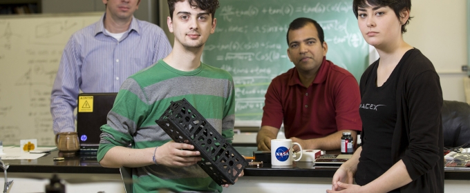 photo of four people in lab, man in foreground with small rectangular box
