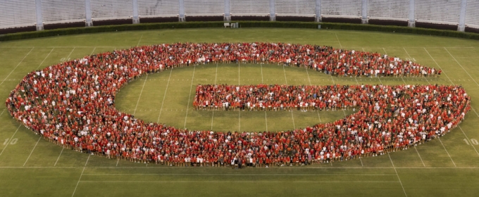 photo of people forming the letter G on a stadium grass field