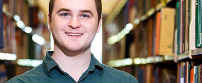 man with library shelves and books