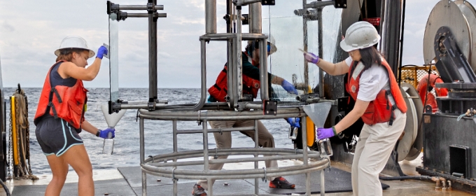 photo of equipment and people on board a ship, sea in background, day